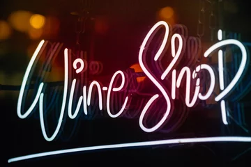 Glowing wine shop neon sign at night on London street, UK
