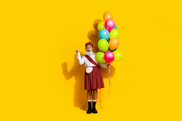 Scottish man in traditional attire with colorful balloons on vivid yellow background showcasing joy...