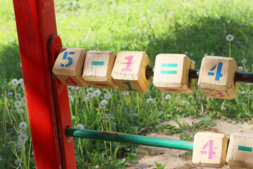 Closeup of wooden educational blocks with numbers and math symbols on a playground. Outdoor...