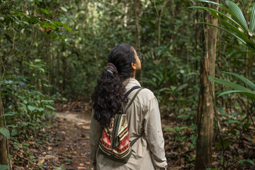 Female explorer walking and observing in the middle of the Amazon rainforest