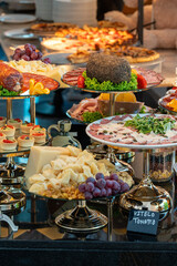 A variety of dishes displayed on a restaurant buffet table. The assortment includes diverse cuisines, vibrant colors, and appetizing presentations, perfect for showcasing abundant dining options and h