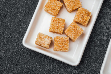 Brown sugar cubes arranged neatly on a white plate for dessert use