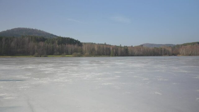 A frozen lake surrounded by coniferous trees in wilderness