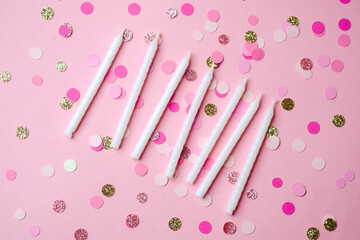 Birthday candles and confetti on a pink background for a festive celebration