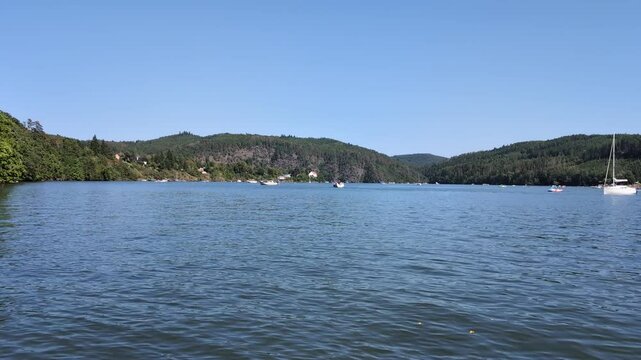 A lake with boats surrounded by tree crowns on a sunny day