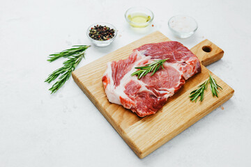 Fresh pork steak with rosemary on wooden cutting board