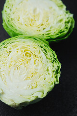 Two cut cabbage halves on dark background close detail