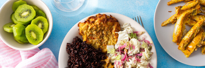 A balanced and nutritious breakfast with brown rice, baked white fish, fresh zucchini-carrot pancakes, a Chinese cabbage salad, and a sweet kiwi dessert, providing a perfect energy boost, banner