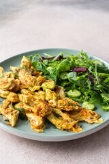 Fried zucchini flowers in batter and mix salad with cucumbers close up