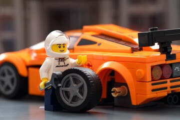 Fototapeta premium Tambov, Russian Federation - January 05, 2025 Lego driver minifigure changing wheel of his Lego Speed Champions McLaren F1 LM car.