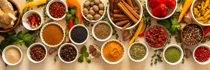 Variety of vibrant spices and dried herbs arranged on a beige backdrop, essential for culinary seasoning and enriching dishes with aromatic, natural flavors, banner