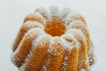 Golden bundt cake close  up on white stand with white stone background