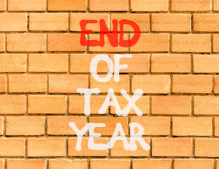End of tax year symbol. Concept words phrase End of tax year on beautiful brown brick wall....