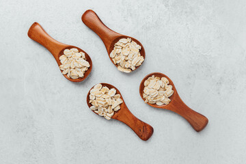 Wooden spoons filled with raw oats arranged on a gray surface