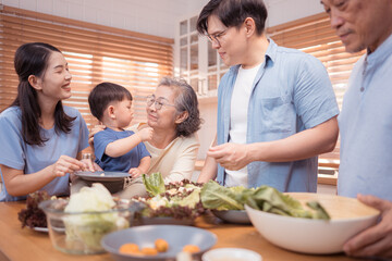 Happy Asian family preparing food together in a bright kitchen,