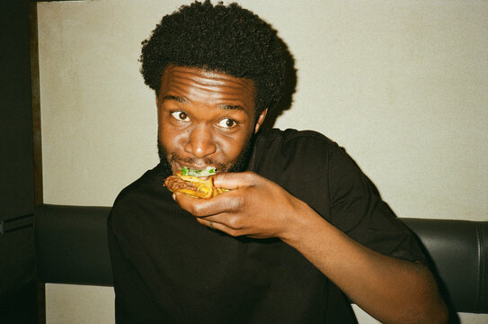 Young man with curly hair eating tacos at fast food restaurant