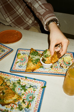 High angle view of man dipping fresh taco in sauce while sitting at restaurant