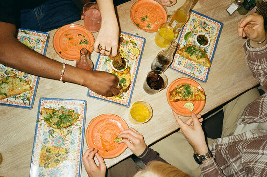 Directly above view of friends enjoying fresh tacos at fast food restaurant