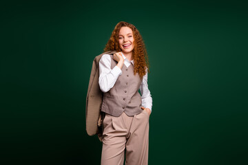 Confident young businesswoman wearing elegant attire standing against a green background while...