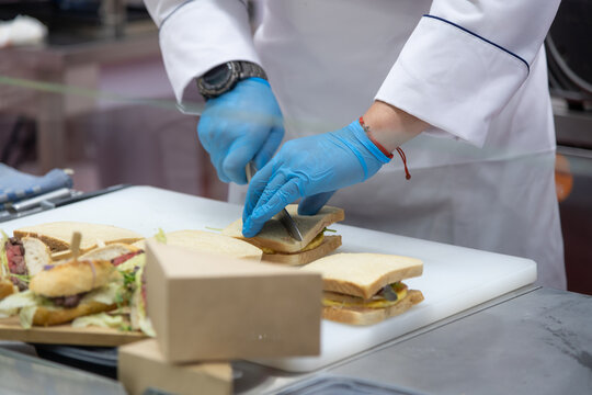 Chef prepares sandwiches in a commercial kitchen during busy lunch hour - Powered by Adobe