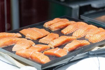 Freshly sliced salmon displayed on black tray at culinary market