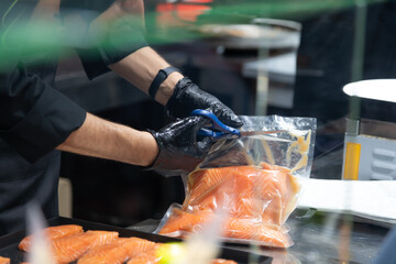 Chef preparing fresh salmon fillets in a commercial kitchen at lunchtime