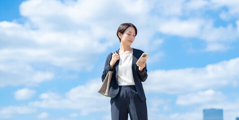 ビジネス　女性　スマホ　青空