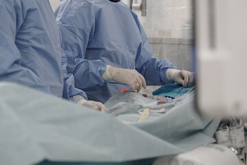 Surgeon in sterile gown and gloves performs procedure in operating room. Surgical instruments,...