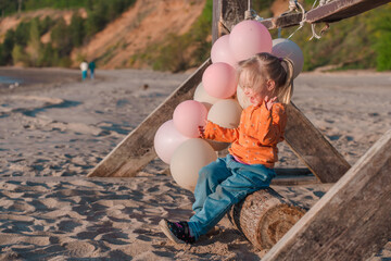 Cute little child runs with balloons by the sea with beautiful scenery