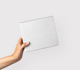 Obraz premium Woman hand hold the white corrugated box on white background. Young woman hand holding small brown rectangular box on white isolated background.
