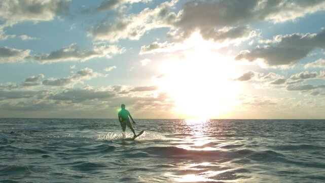 Sun glowing across sea with water hoverboard soaring over it at 1000 FPS