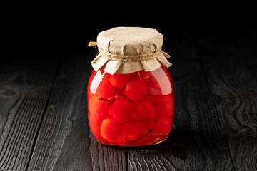 Jar of Pickled Cherries on Dark Wooden Background