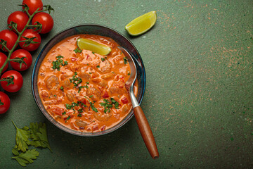 Authentic Brazilian moqueca de camarao, a rich seafood stew with shrimp, tomatoes, peppers, and lime, garnished with parsley and served in a rustic bowl on dark green background, copy space