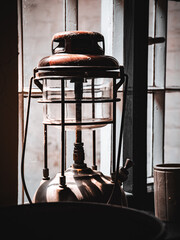 Vintage lantern casting shadows beside a rustic window on a sunny day.