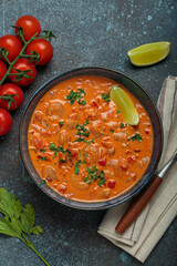Authentic Brazilian moqueca de camarao, a rich seafood stew with shrimp, tomatoes, peppers, and lime, garnished with parsley and served in a rustic bowl on dark blue background