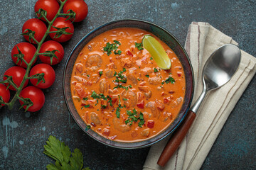 Authentic Brazilian moqueca de camarao, a rich seafood stew with shrimp, tomatoes, peppers, and lime, garnished with parsley and served in a rustic bowl on dark blue background