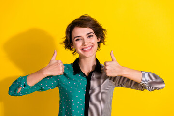 Photo of cheerful glad lovely girl wear stylish striped clothes thumb up sign isolated on yellow color background