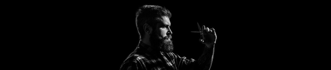 Male in barbershop, haircut, shaving, barber scissors. Bearded man isolated on black background. Mans haircut in barber shop. Barber scissors, barber shop. Black and white.