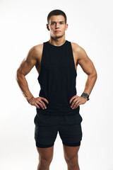 Fototapeta premium Vertical photo of strong and confident man wearing athletic black outfit, standing proudly with hands on hips and looking directly into the camera, showcasing fitness and determination.