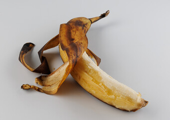 Overripe banana. Half-peeled banana with darkened skin on white background.