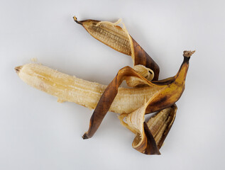 Overripe banana. Half-peeled banana with darkened skin on white background.