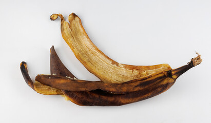 Darkened banana peel with brown spots on white background. Overripe banana.