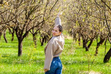 Picture on a spring background with a very bright and beautiful sun as a beautiful girl in blue jeans walks and relaxes from problems. NATURE IS A MEDICINE FOR THE LIFE AND HEALTH OF A MAN. WE PROTECT