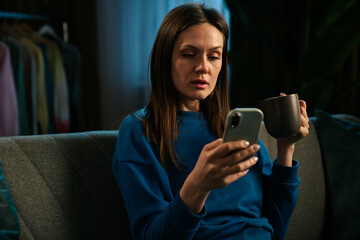 Woman Relaxing on Sofa Enjoying Coffee and Smartphone Interaction