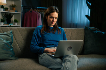 Woman Sitting on a Sofa with Laptop During Evening Time