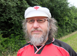 Portrait of a 60-year-old German man, expressing his love for Canada with the maple leaf on his white cap.