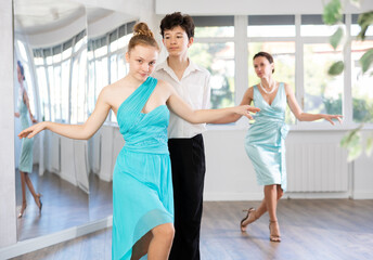 Dance teacher teaches a girl and boy couples ballroom dancing