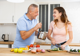 Happy father spending time with adult daughter - preparing lunch together in the kitchen