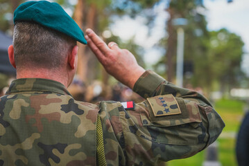 A Polish soldier saluting and seen from behind.