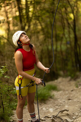 A woman in a red top and yellow shorts is holding a rope